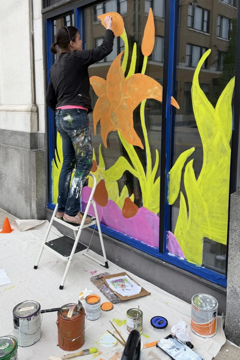 Kelly Witte painting her floral window art display for the Makers' Gallery